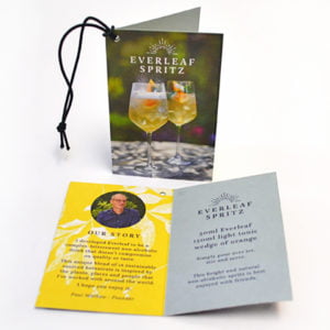 Folded swing tags with custom branding and barcode for UK retail, featuring durable lamination, eyelets for easy hanging, and detailed design showcasing prices and product information.